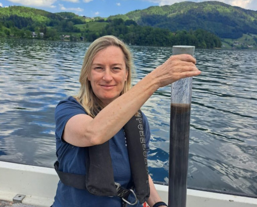 Suzanne McGowan holding a glass tube with a lake sample